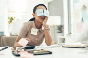 Shot of a young businesswoman covered in sticky notes while working on her taxes in an office